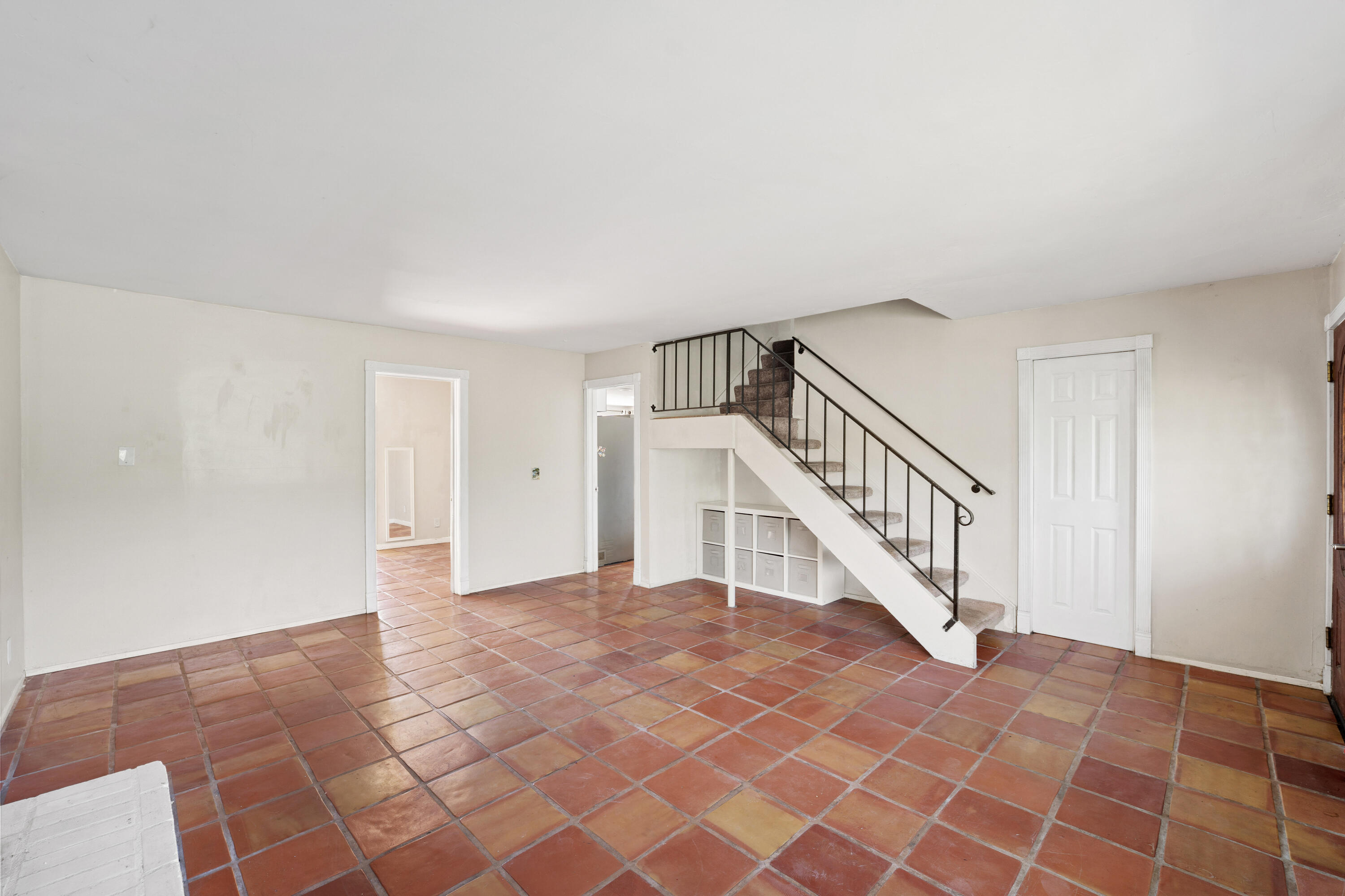 Vacant room with terracotta tile floors, a staircase, and built-in storage beneath the stairs.