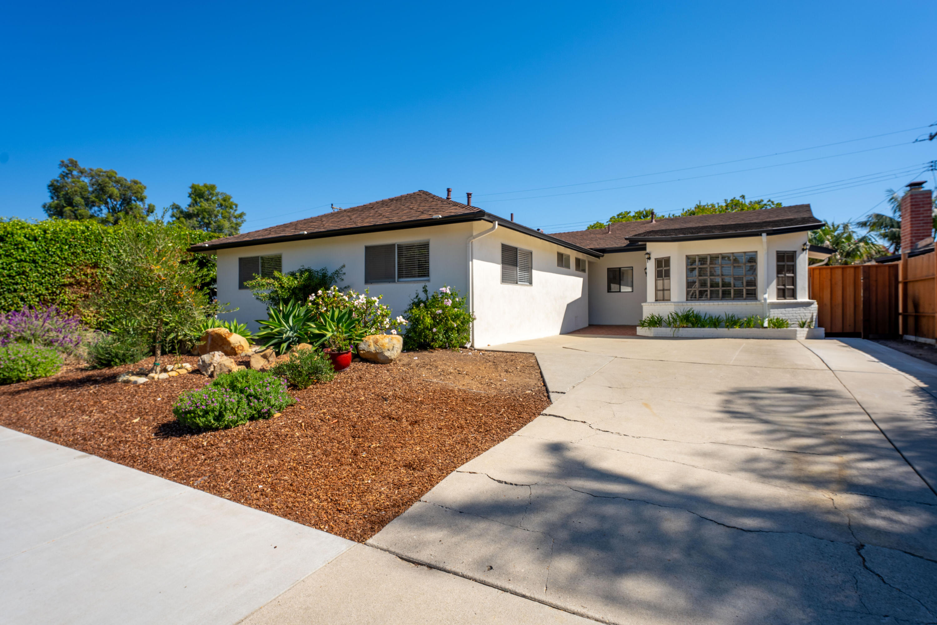 Single-story white stucco home with a wide driveway and landscaped front yard.