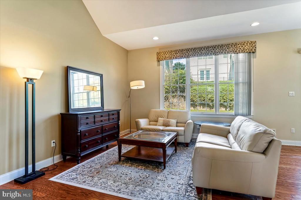 Living room with cream leather sofas, a patterned rug, and a large window overlooking greenery.