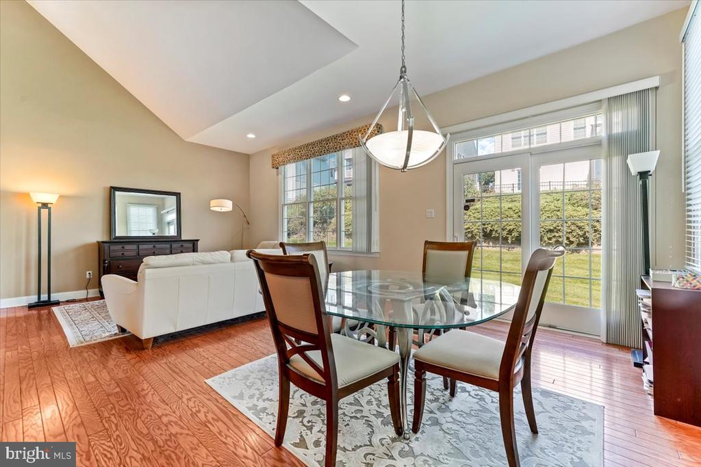 Dining and living area with a glass table, white sofa, and sliding doors to the yard.