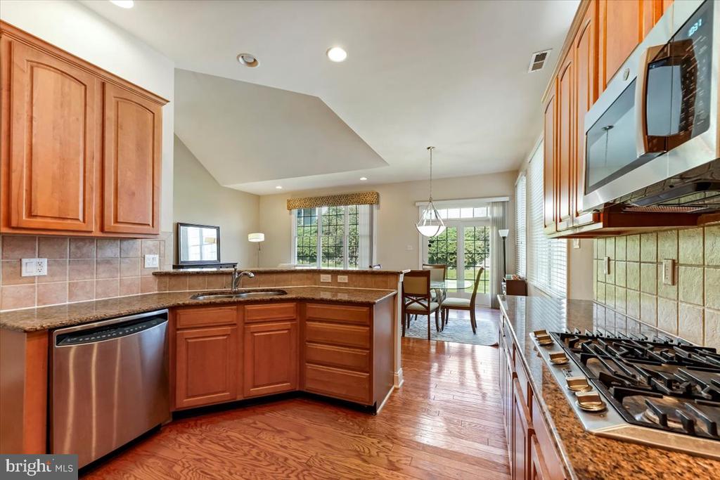 Kitchen with wood cabinets, granite counters, stainless appliances, and an adjoining dining area.