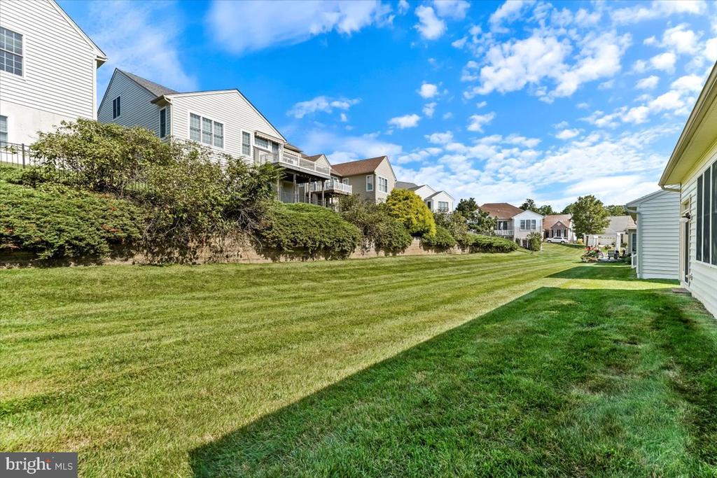 Broad mowed lawn between neighboring homes, with shrubs lining one side.