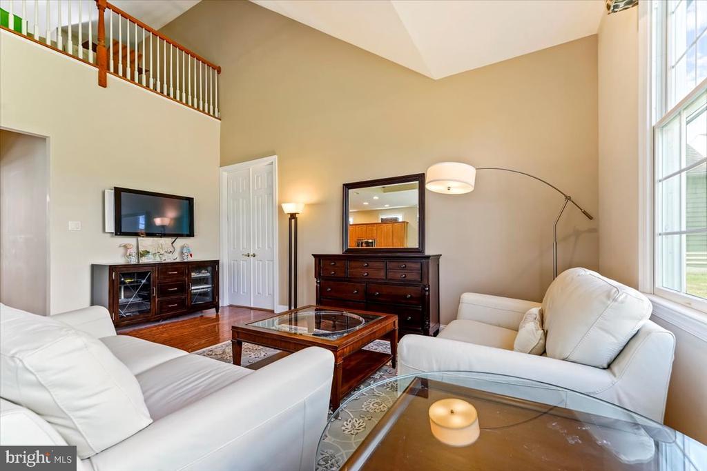 Living room with white sofas, a vaulted ceiling, and tall windows.