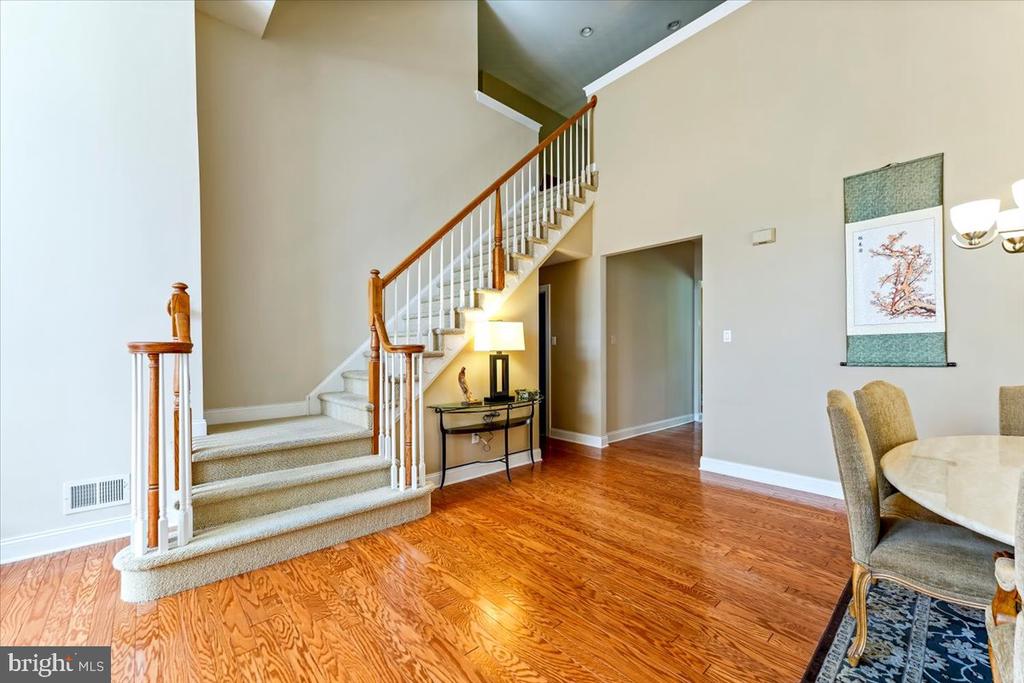 Foyer with a carpeted staircase, wood handrail, and glossy hardwood floors.