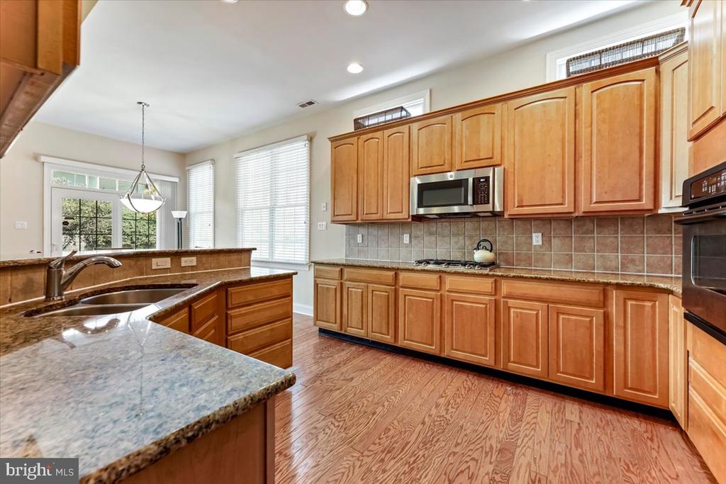 Kitchen with wood cabinets, granite counters, a breakfast peninsula, stainless appliances, and hardwood floors.