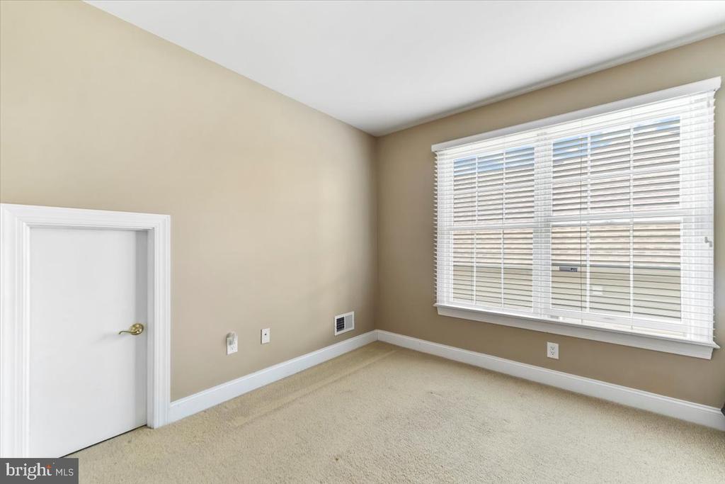 Empty room with beige walls, carpet, and a large window with white blinds.