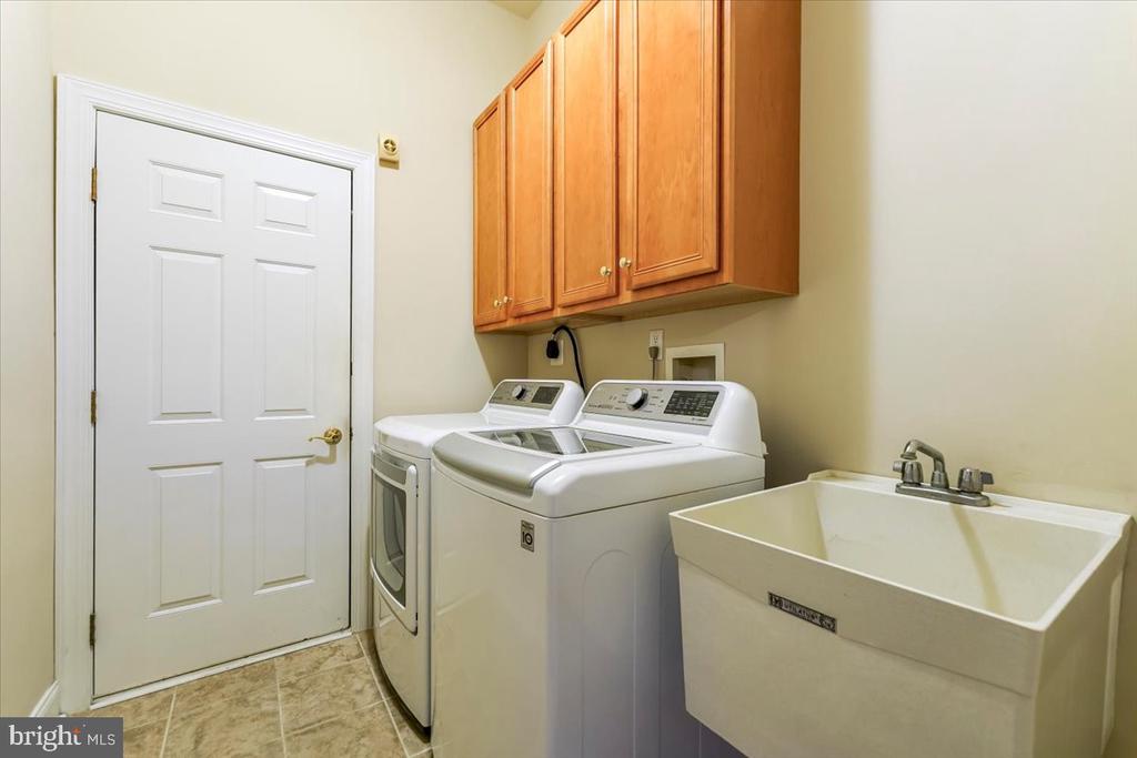 Laundry room with washer, dryer, overhead wood cabinets, and a deep utility sink.