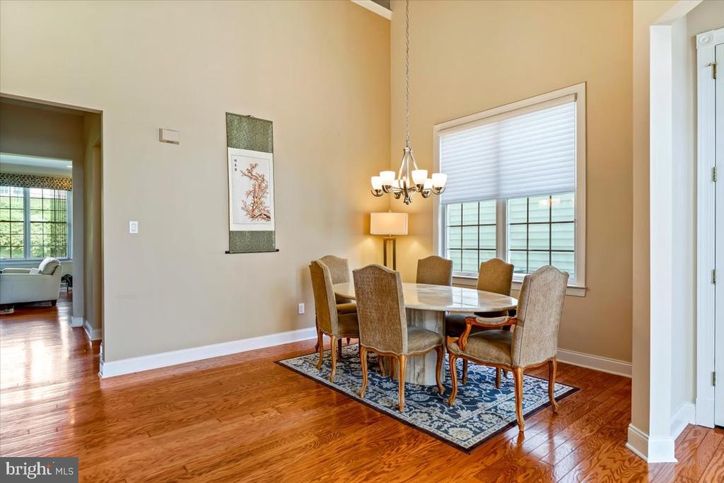 Dining room with a round table, chandelier, patterned rug, and polished hardwood floors.