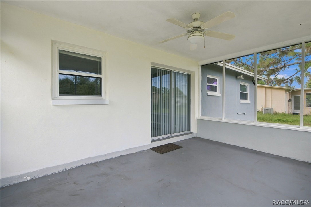 Screened patio with a ceiling fan, sliding glass door, and view of the yard.