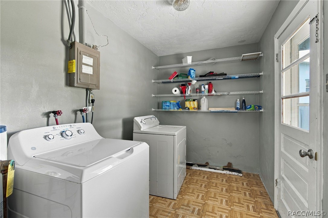 Laundry room with a top-loading washer, dryer, wire storage shelves, and a white door.