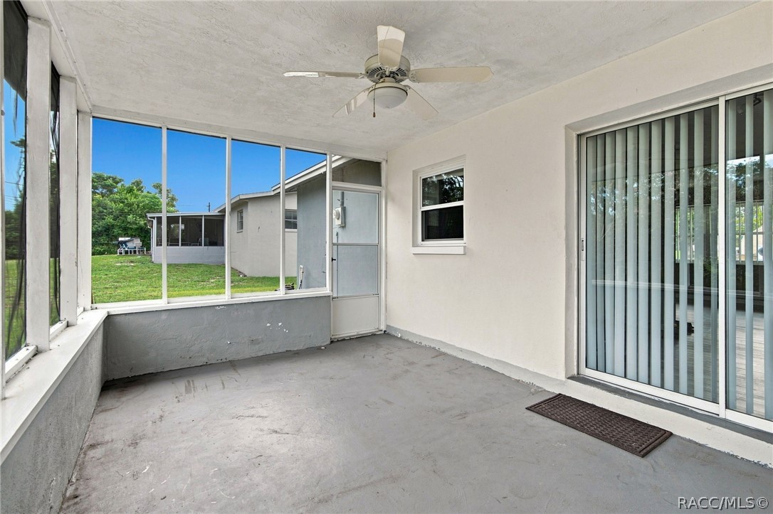 Enclosed porch with screened windows, a ceiling fan, and a view of the grassy yard.