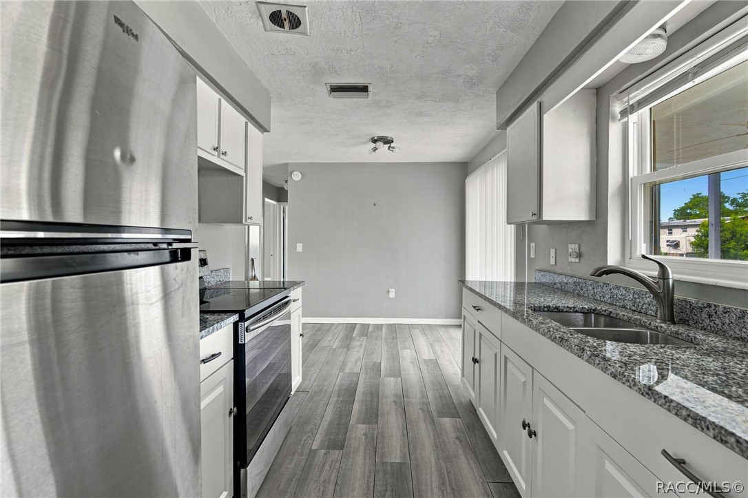 Kitchen with stainless steel appliances, granite counters, and a double-basin sink beneath a window.