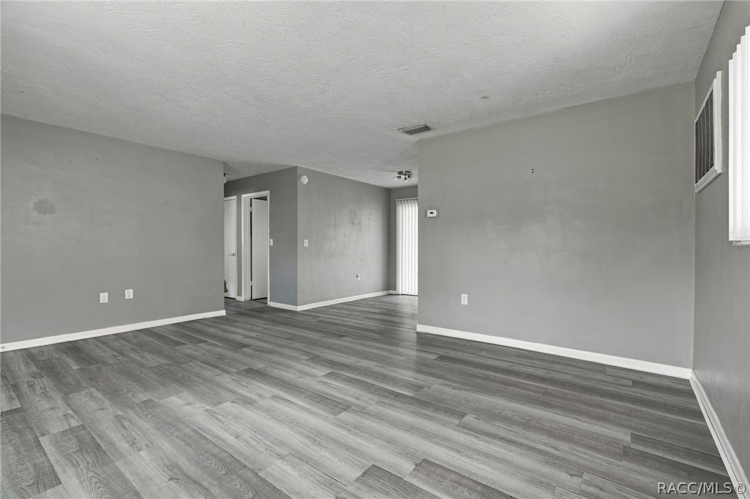 Vacant living room with gray wood-look plank flooring and an open doorway.