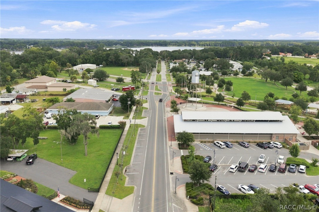 Aerial view of downtown Inverness, with a main avenue, parking lot, and lake in the distance.