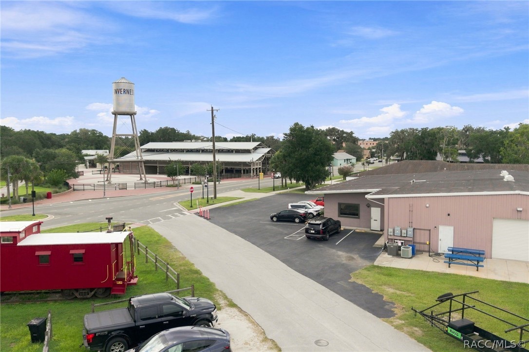 Commercial property with a pink-sided building and parking area, near the Inverness water tower.