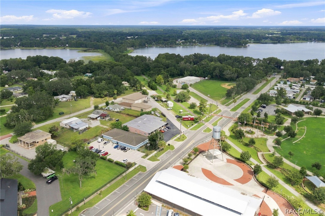 Aerial view of downtown Inverness with its water tower and plaza beside a lake.