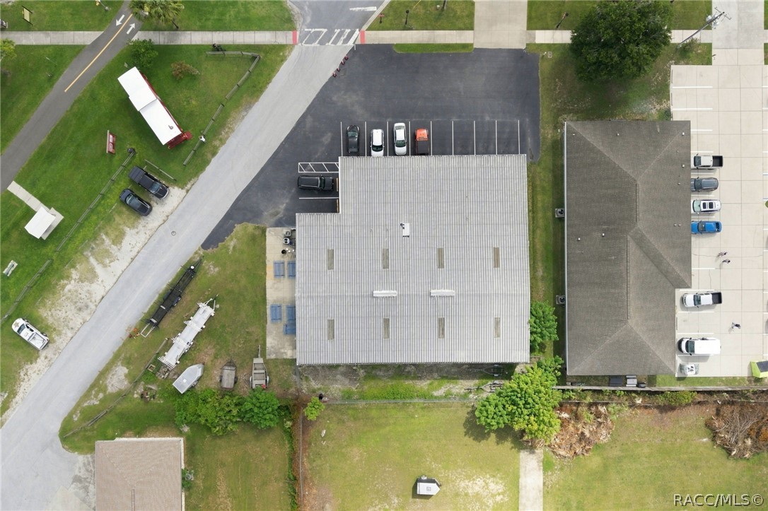Aerial view of a commercial building with a light metal roof and adjacent parking lot.