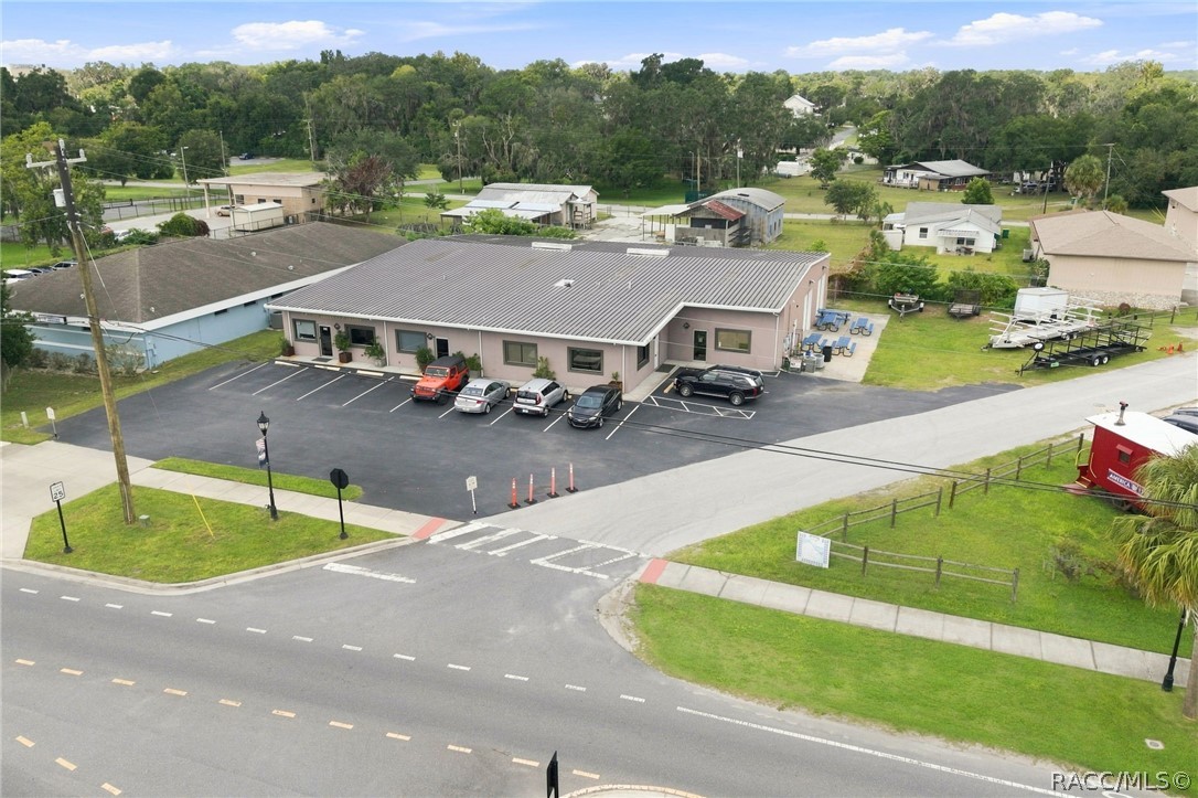 Commercial building with a metal roof and parking lot, viewed from above at a street intersection.