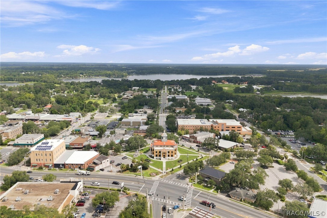 Aerial view of downtown Inverness, with a lake beyond the tree-lined streets.