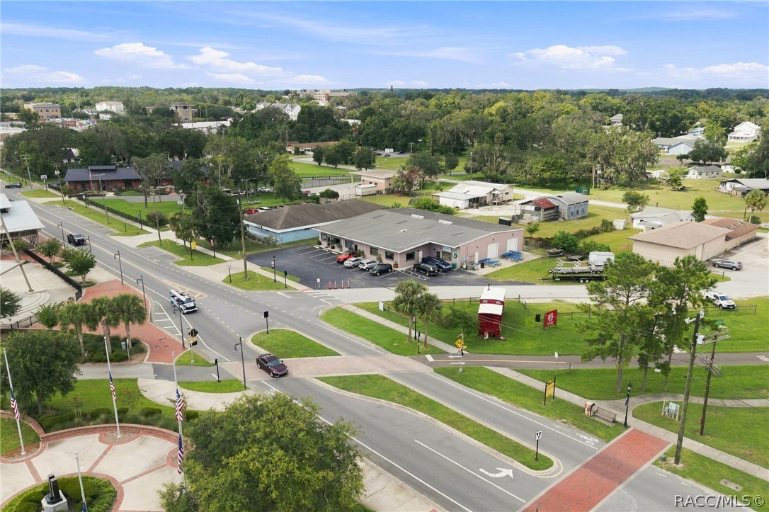 Aerial view of a commercial building beside a road intersection, surrounded by parking lots and trees.