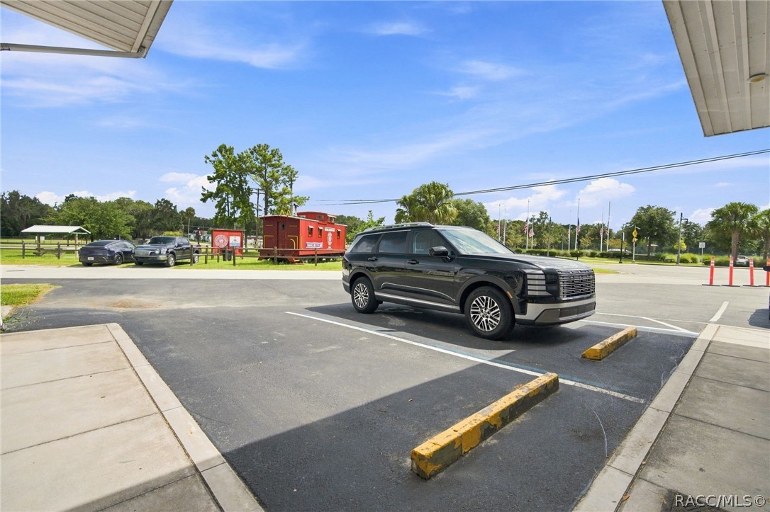 Paved parking lot with marked spaces, a black SUV, and concrete walkways.