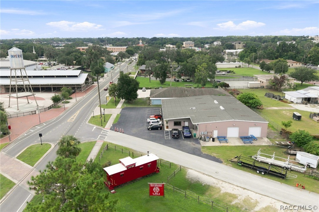 Aerial view of a pink commercial building and red caboose display, with the Inverness water tower nearby.