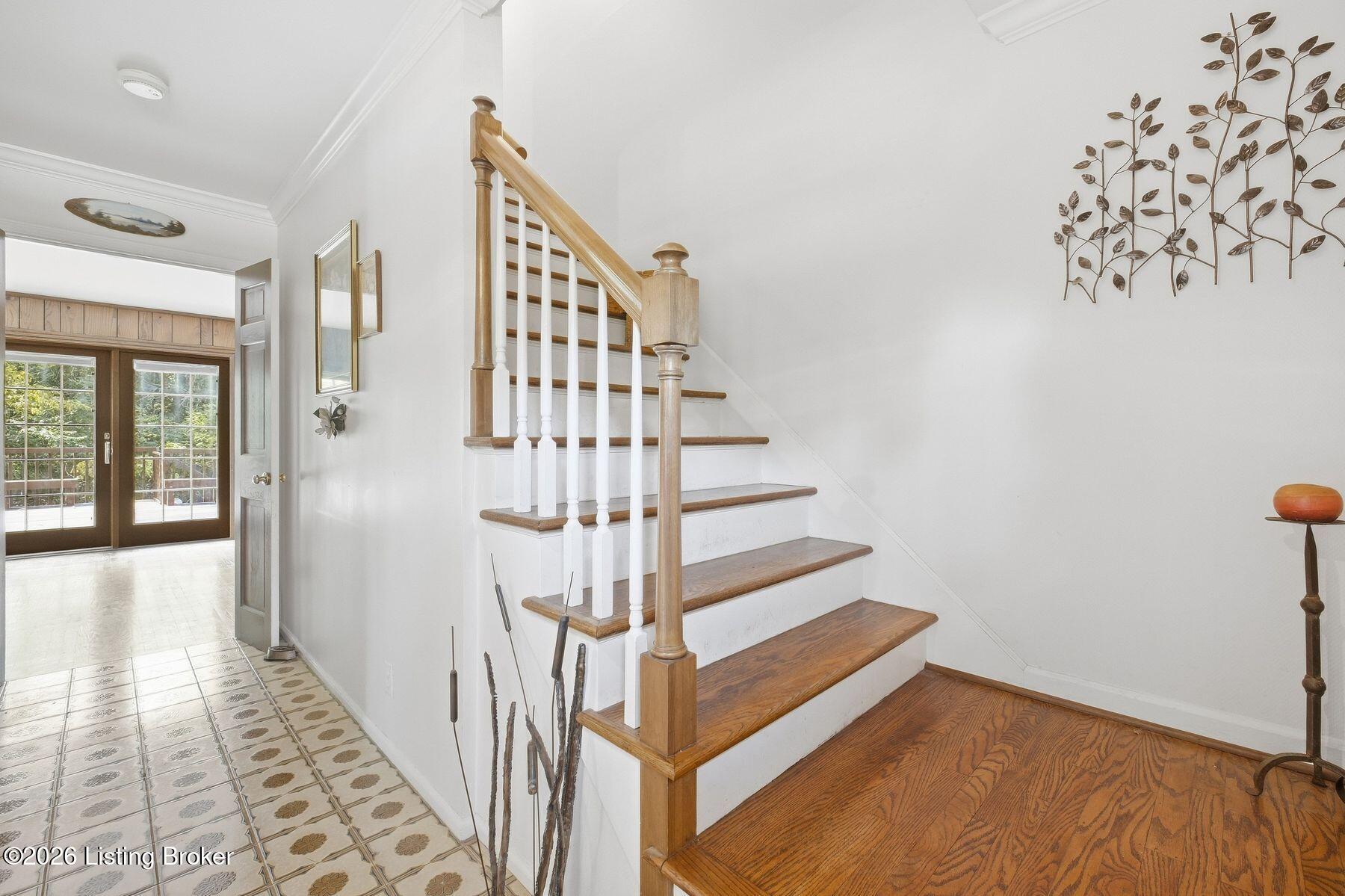 Entry foyer with a wood staircase, patterned tile, and glass-paneled patio doors.