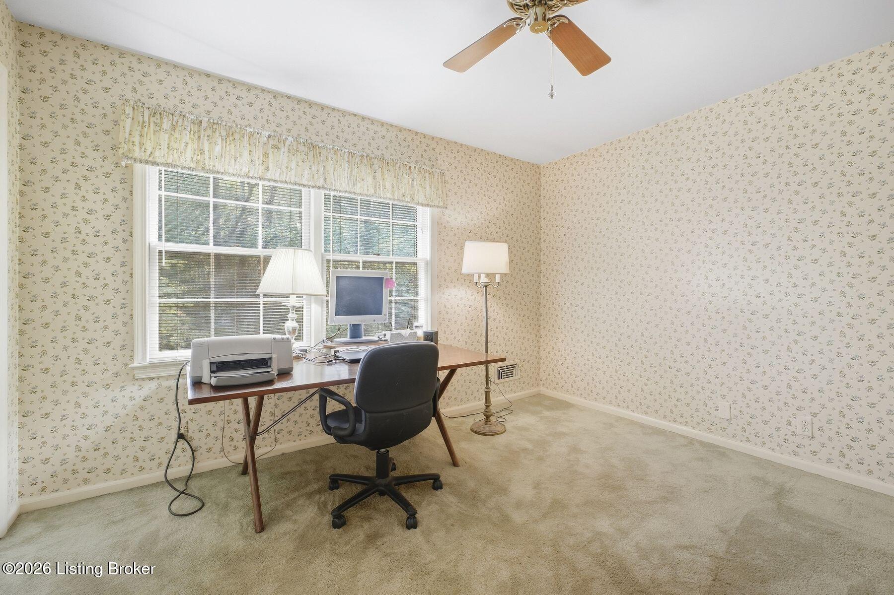 Home office with floral wallpaper, desk, computer, printer, and two bright windows.