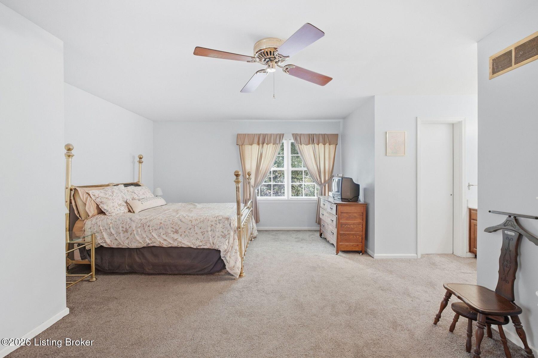 Furnished bedroom with a brass four-poster bed and a window with curtains.