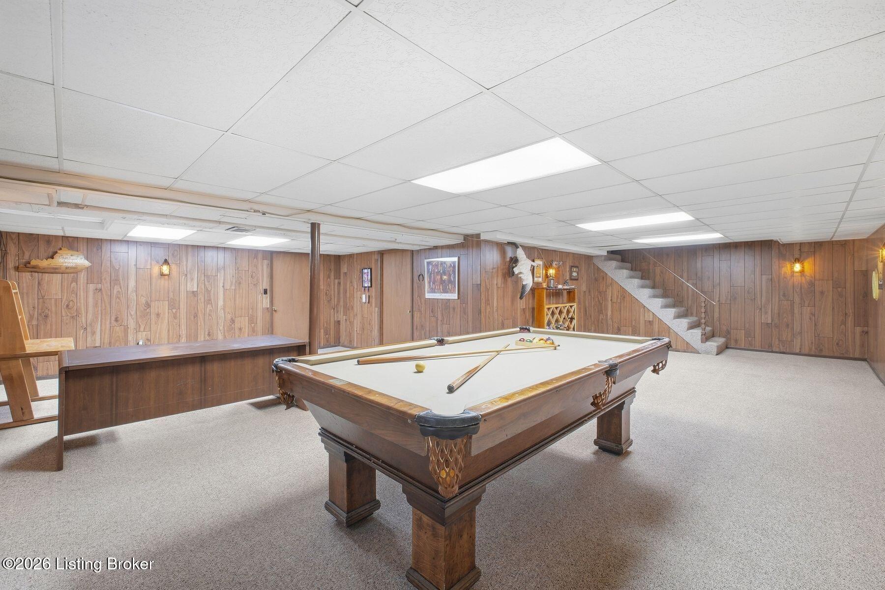 Basement game room with a full-size billiards table, wood-paneled walls, and carpet.
