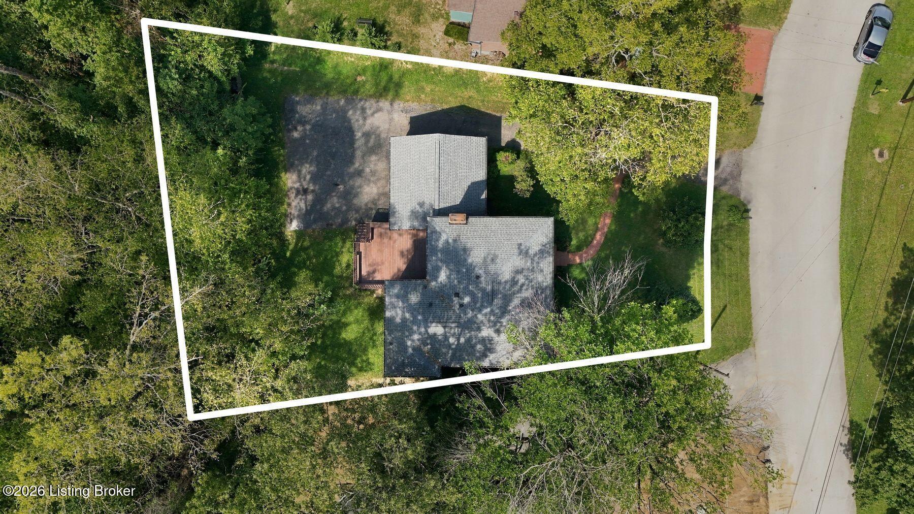 Aerial view of a wooded property with the house and lot outlined in white.