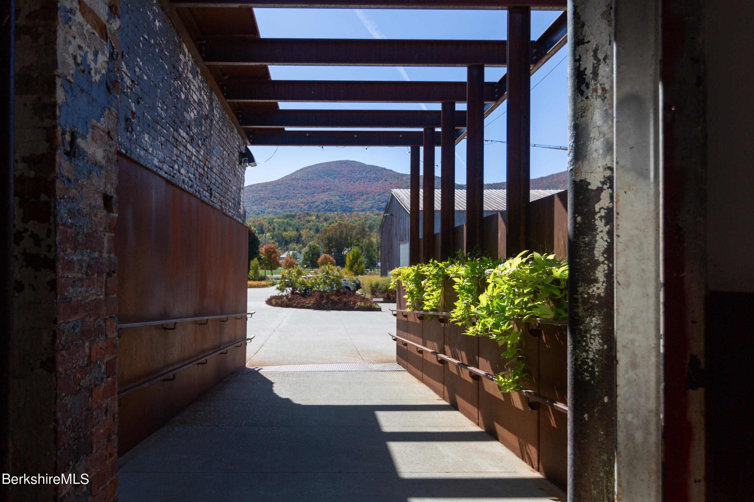 Covered exterior walkway with brick wall, raised planters, and a mountain view.