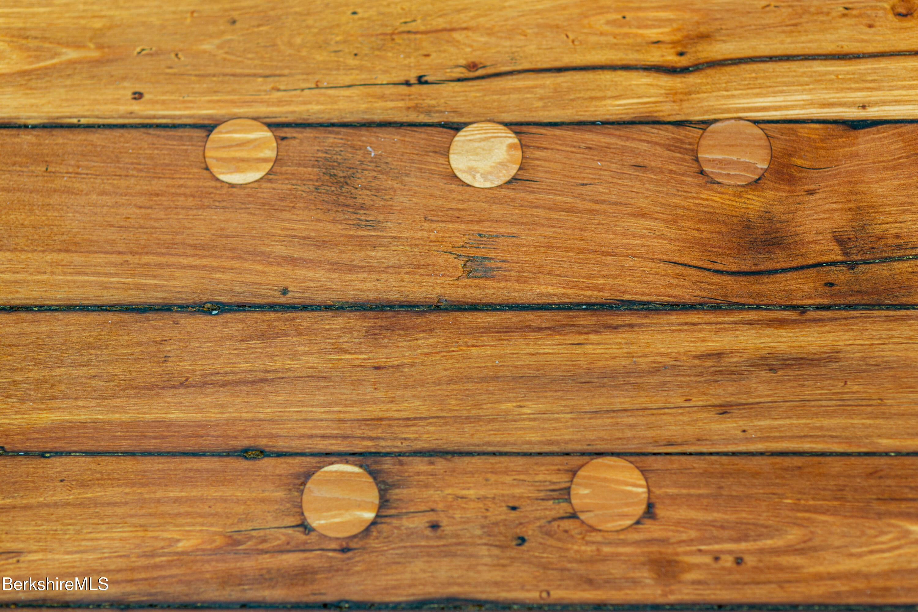 Warm-toned wooden boards with visible grain and several round wood plugs.