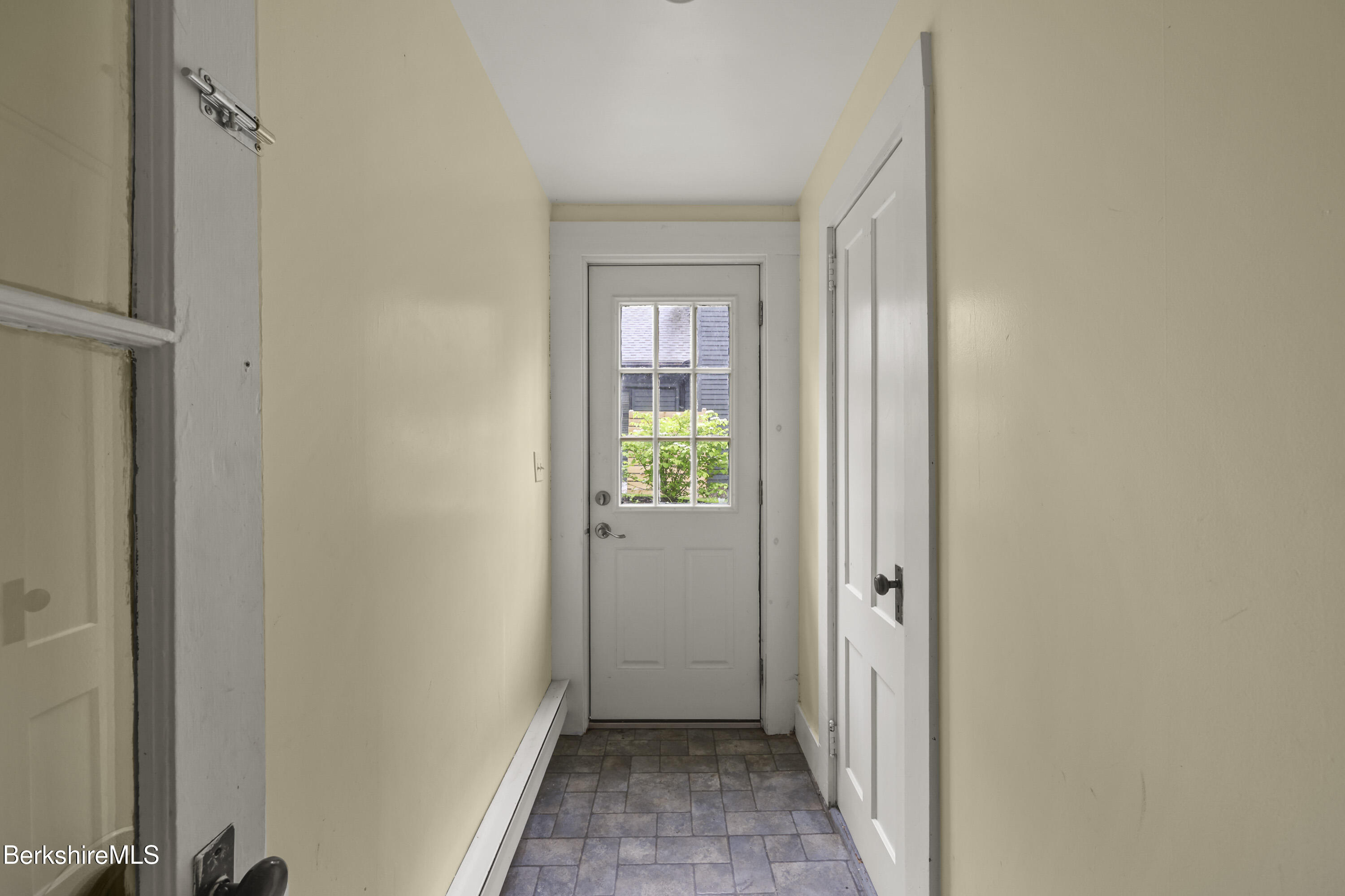 Entry hallway with gray tile flooring and a white multipane exterior door.