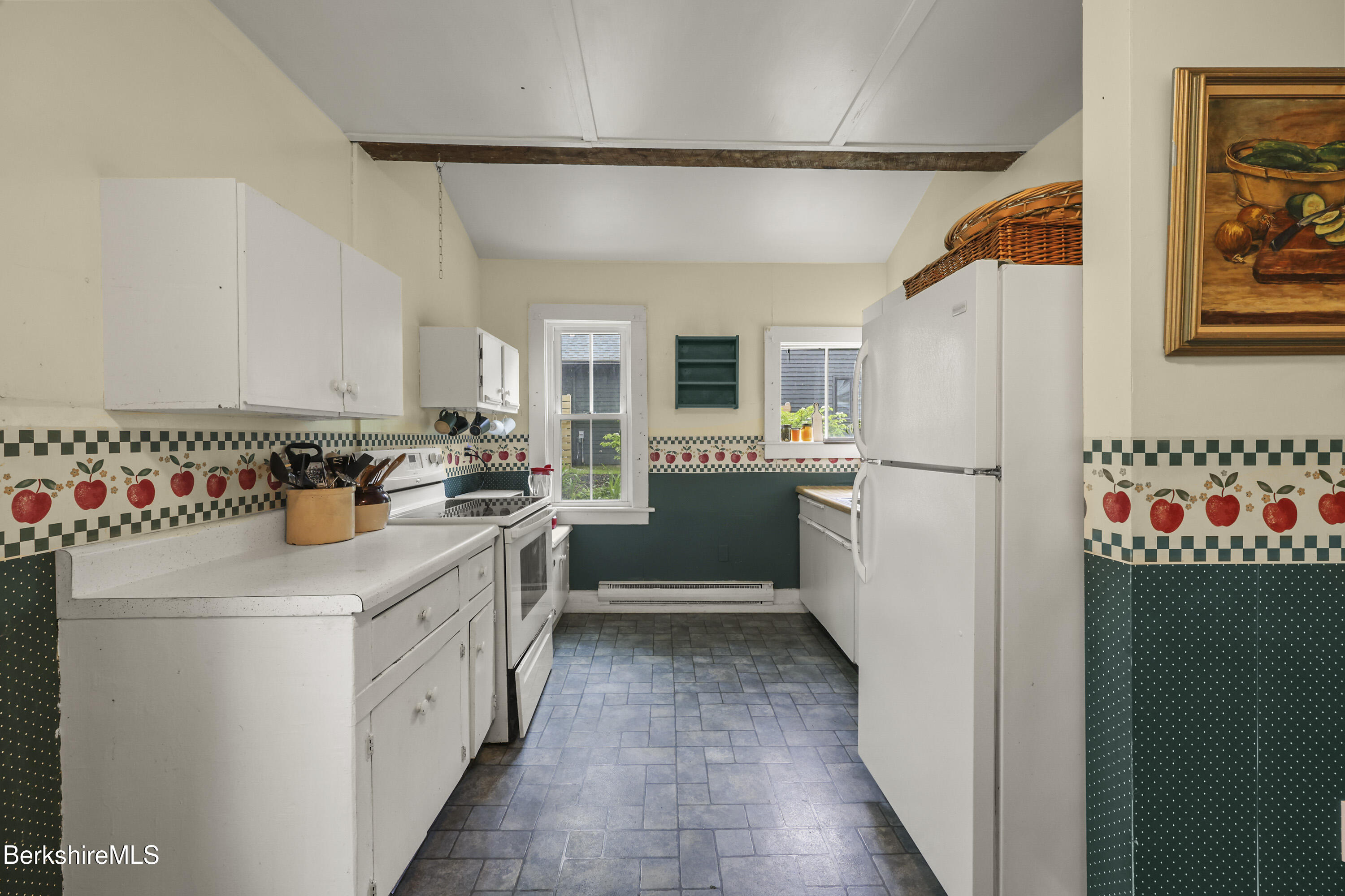Kitchen with white cabinets, blue-gray tile floor, and a distinctive apple-patterned wall border.