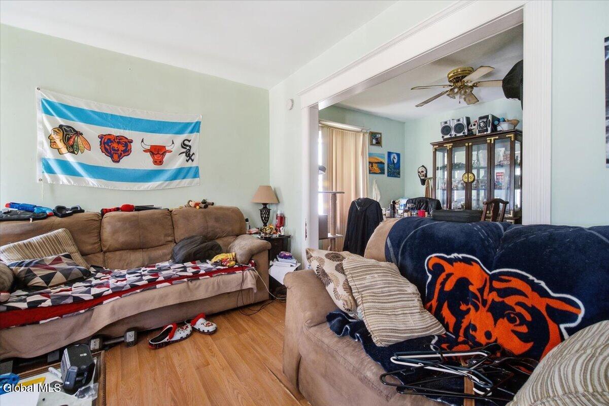 Living room with tan sofas, sports-themed decor, and an adjoining room with a glass-front cabinet.