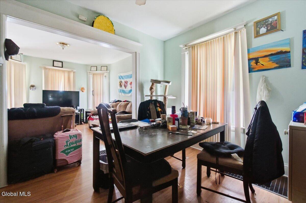 Dining area with dark table and chairs, opening into a living room with sofas and a television.