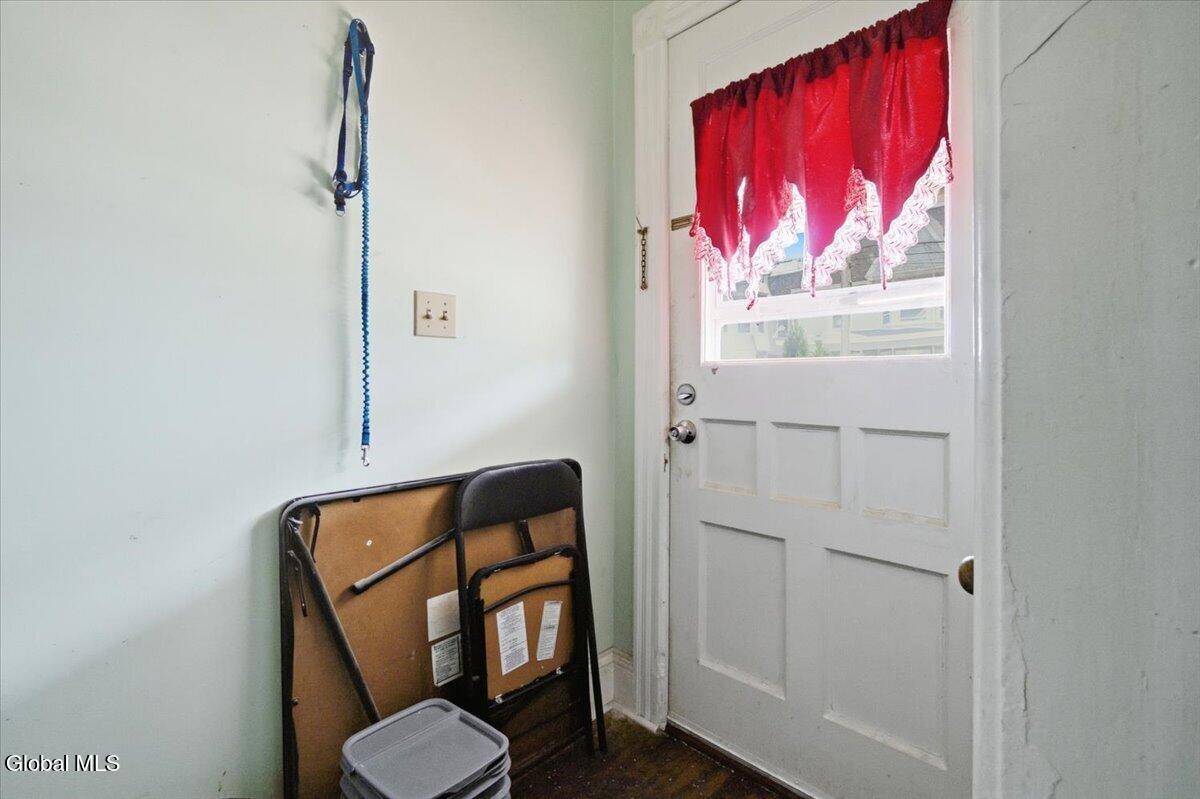 Entry area with a white paneled door, red curtain, and folded bed frame.