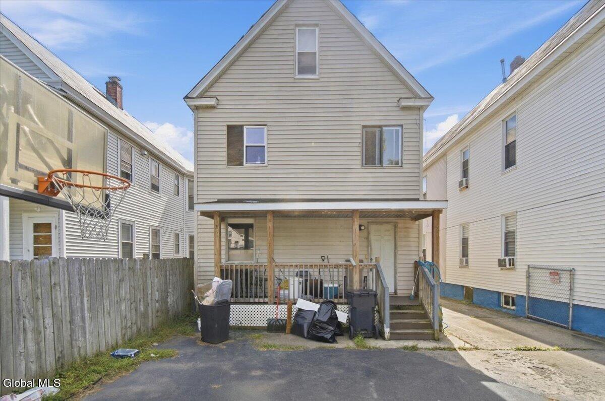 Rear exterior of a two-story house with a covered porch and narrow driveway.