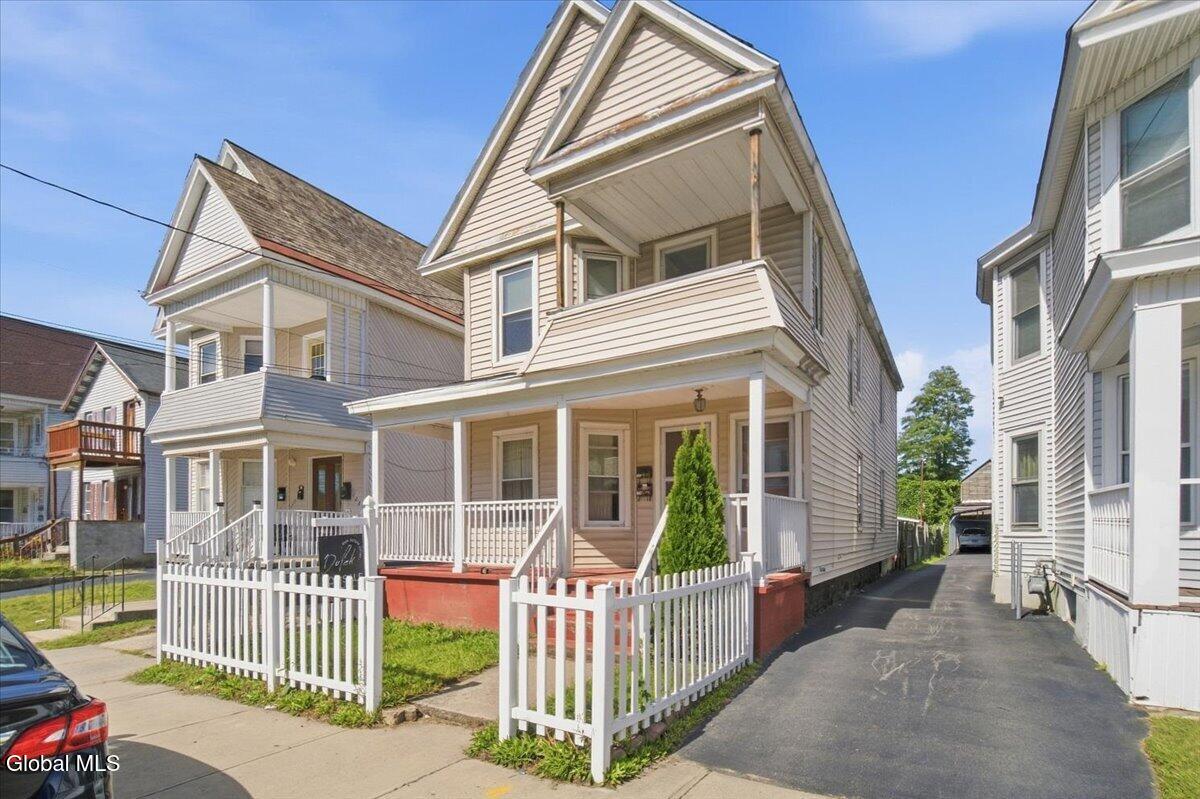 Two-story home with a covered porch, white picket fence, and side driveway.