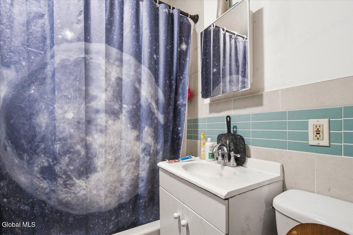 Bathroom with a moon-and-stars shower curtain, aqua tile, white vanity, and toilet.