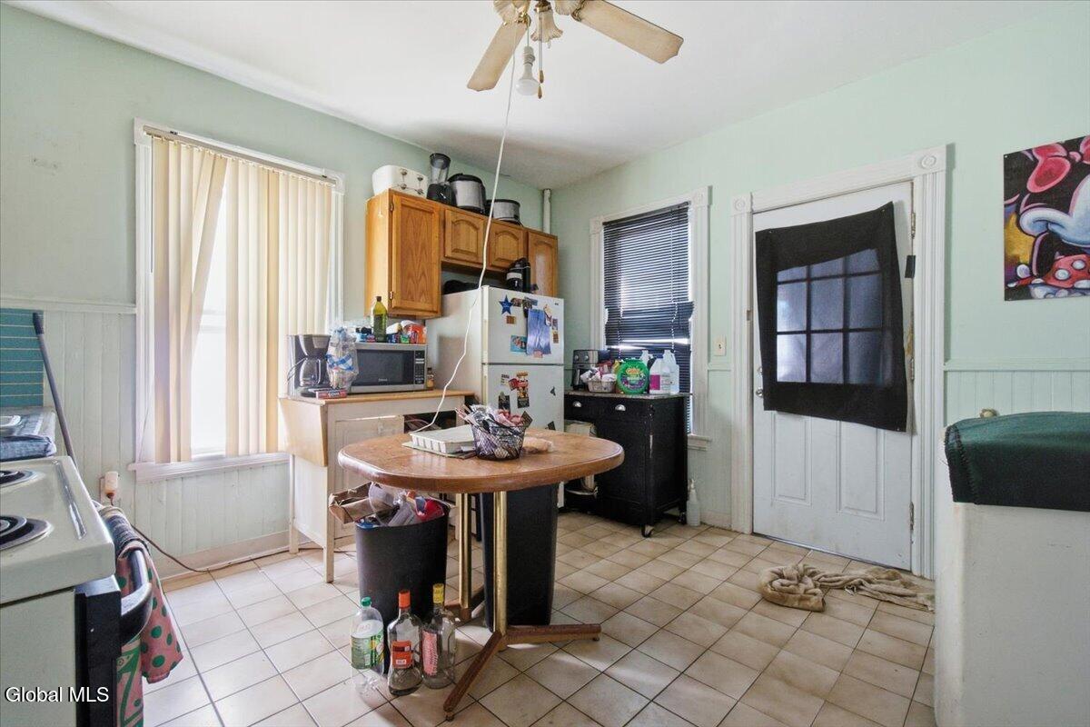 Kitchen with wood cabinets, a round table, tiled floor, and a door covered by a dark curtain.