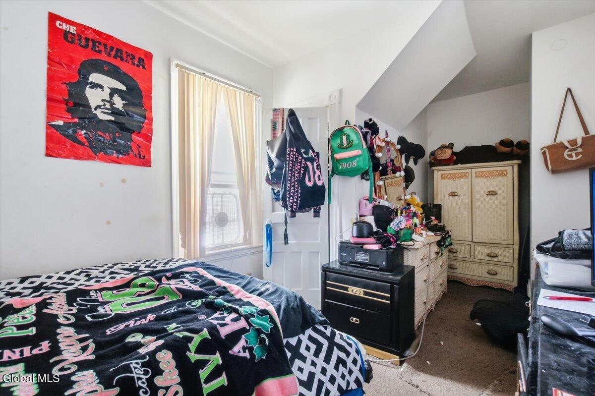 Bedroom with graphic bedding, a red Che Guevara poster, and dressers beneath a sloped ceiling.