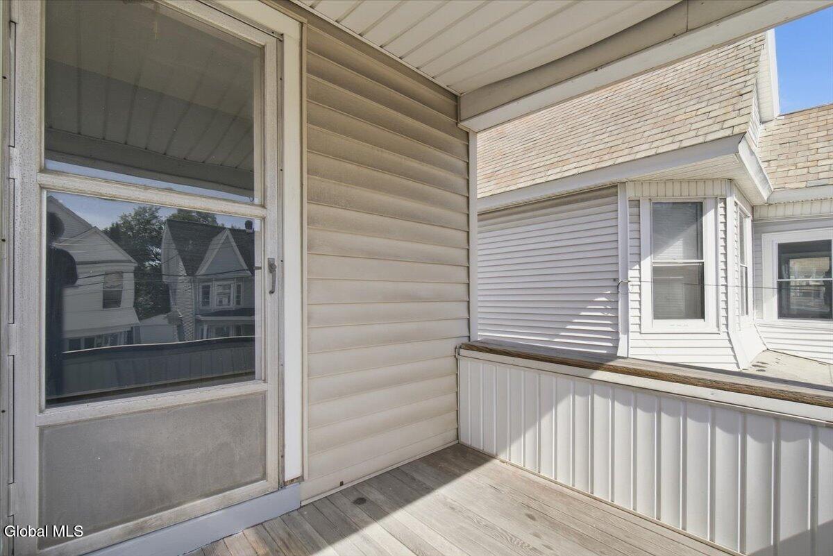 Covered porch with gray flooring, white railing, and a sliding glass door.