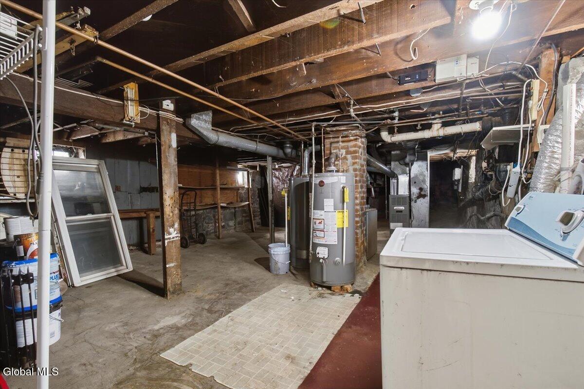 Unfinished basement with exposed beams, a water heater, and a chest freezer.