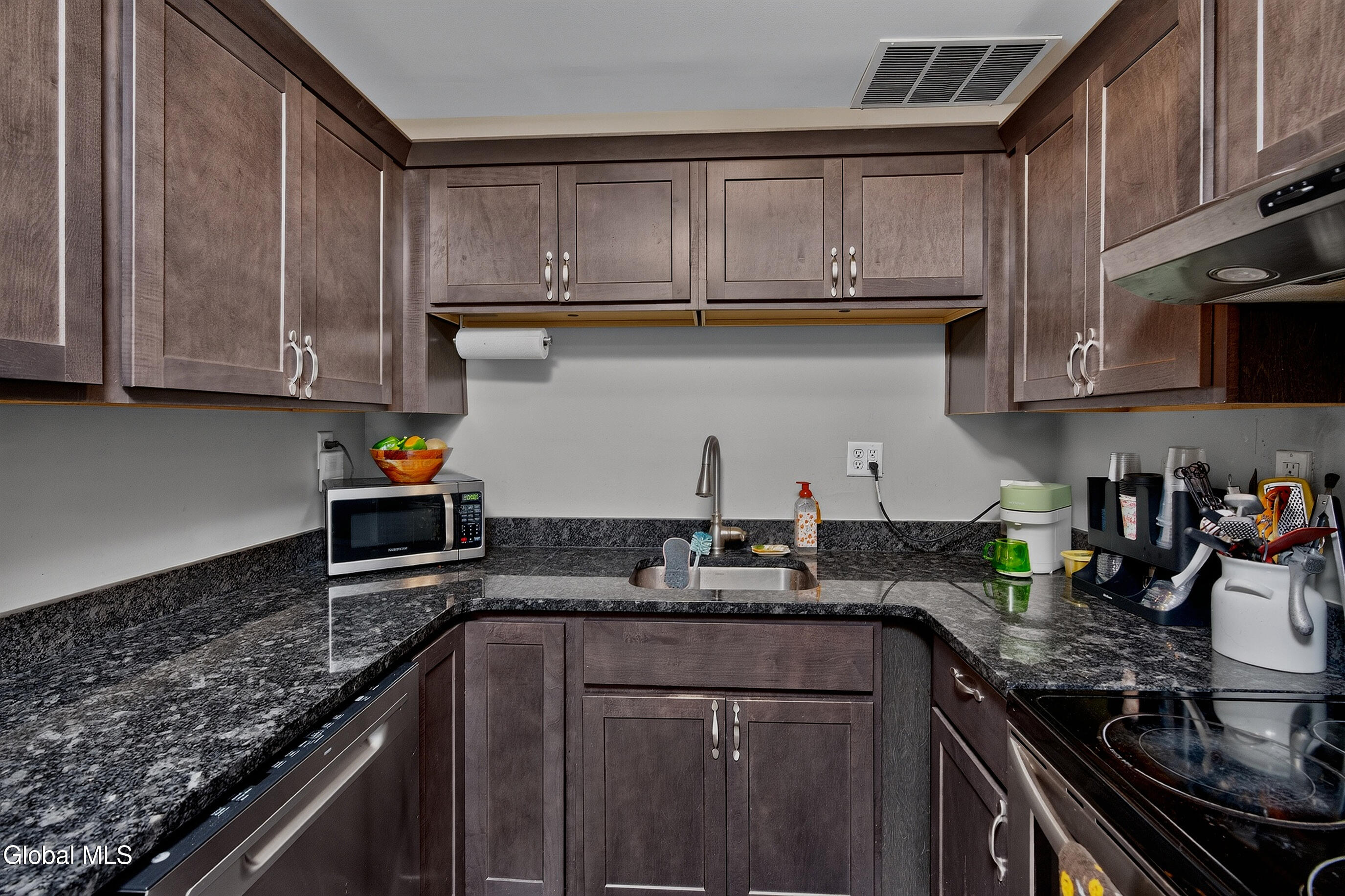 Kitchen with dark wood cabinets, granite counters, and a double-basin sink.