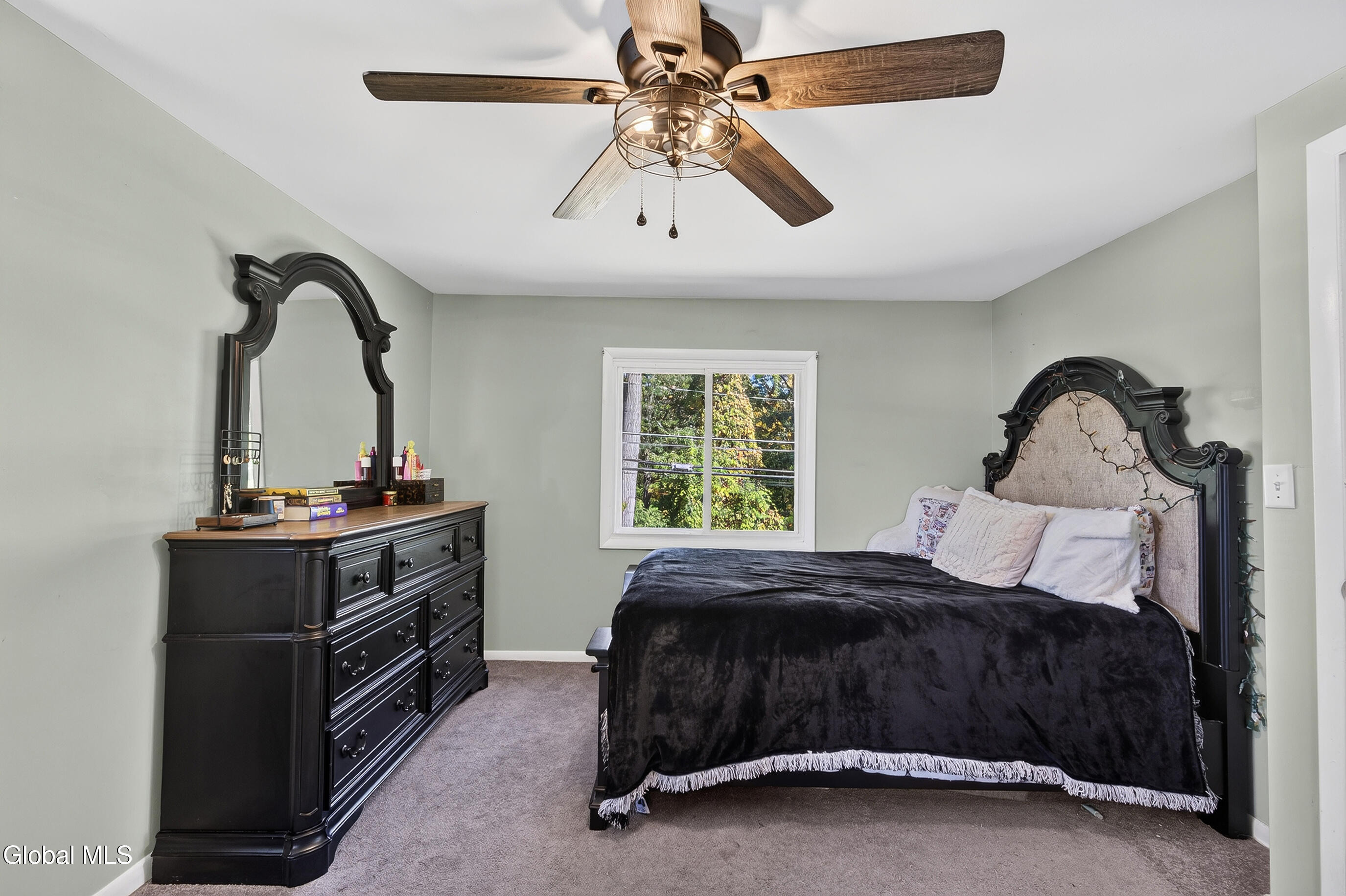 Bedroom with a black-covered bed, ornate dark furniture, and a ceiling fan.