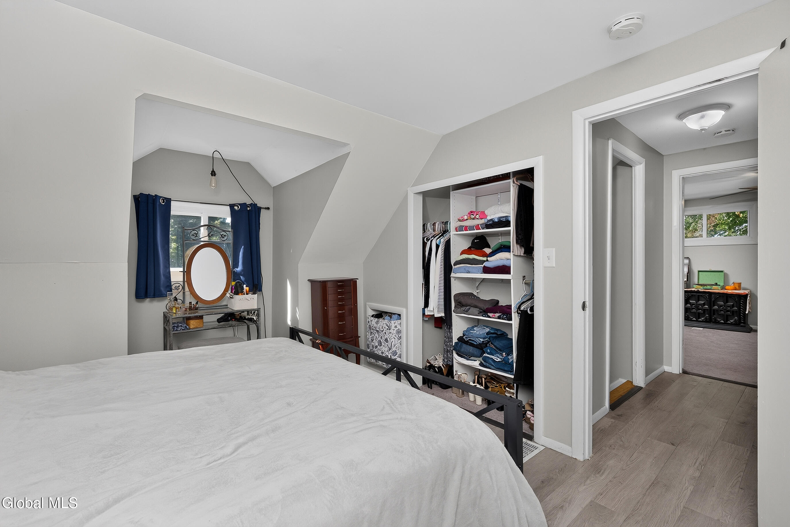Bedroom with a large open clothes closet, sloped ceiling, and doorway to an adjoining room.