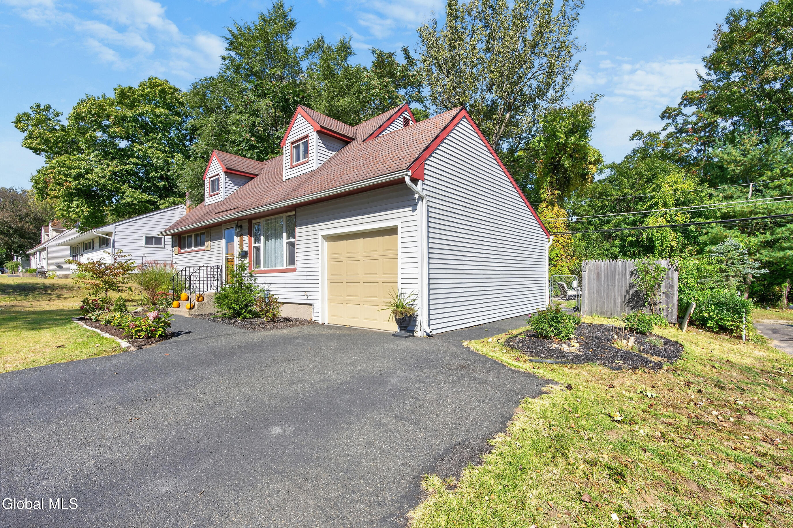 House exterior with red-trimmed dormers, attached garage, and wide driveway.