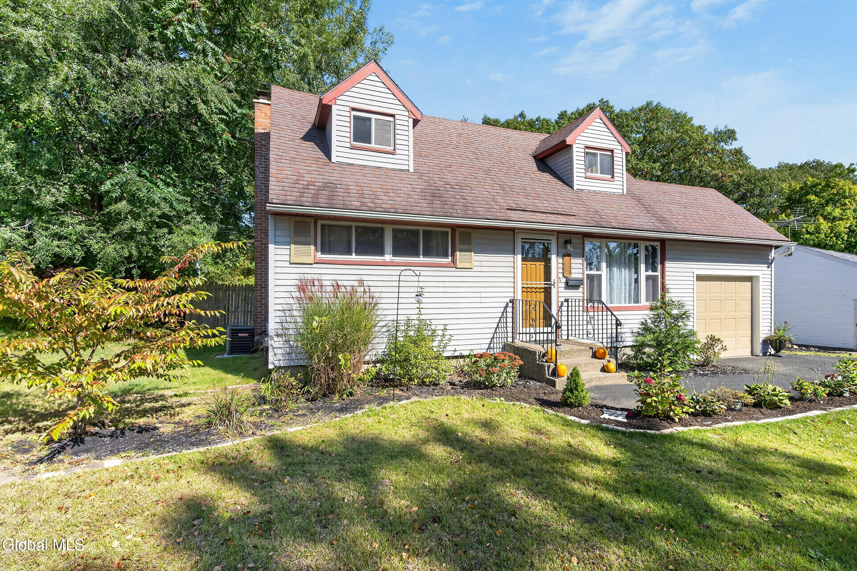 White-sided house with two dormers, attached garage, and landscaped front yard.